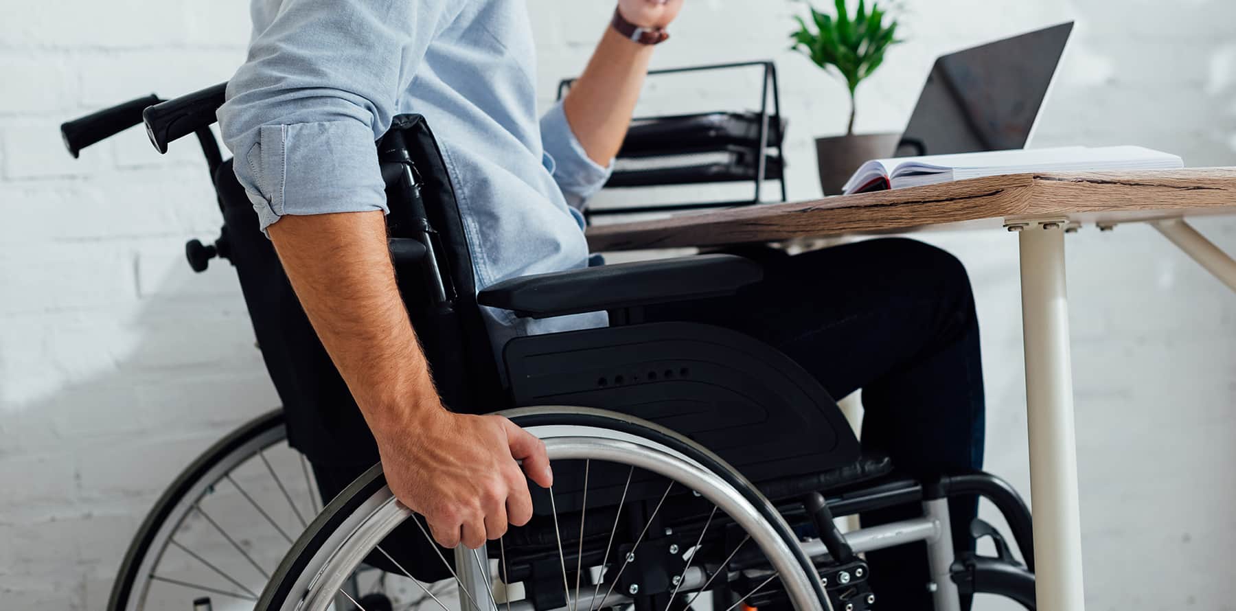 White man sitting in a wheelchair at a desk