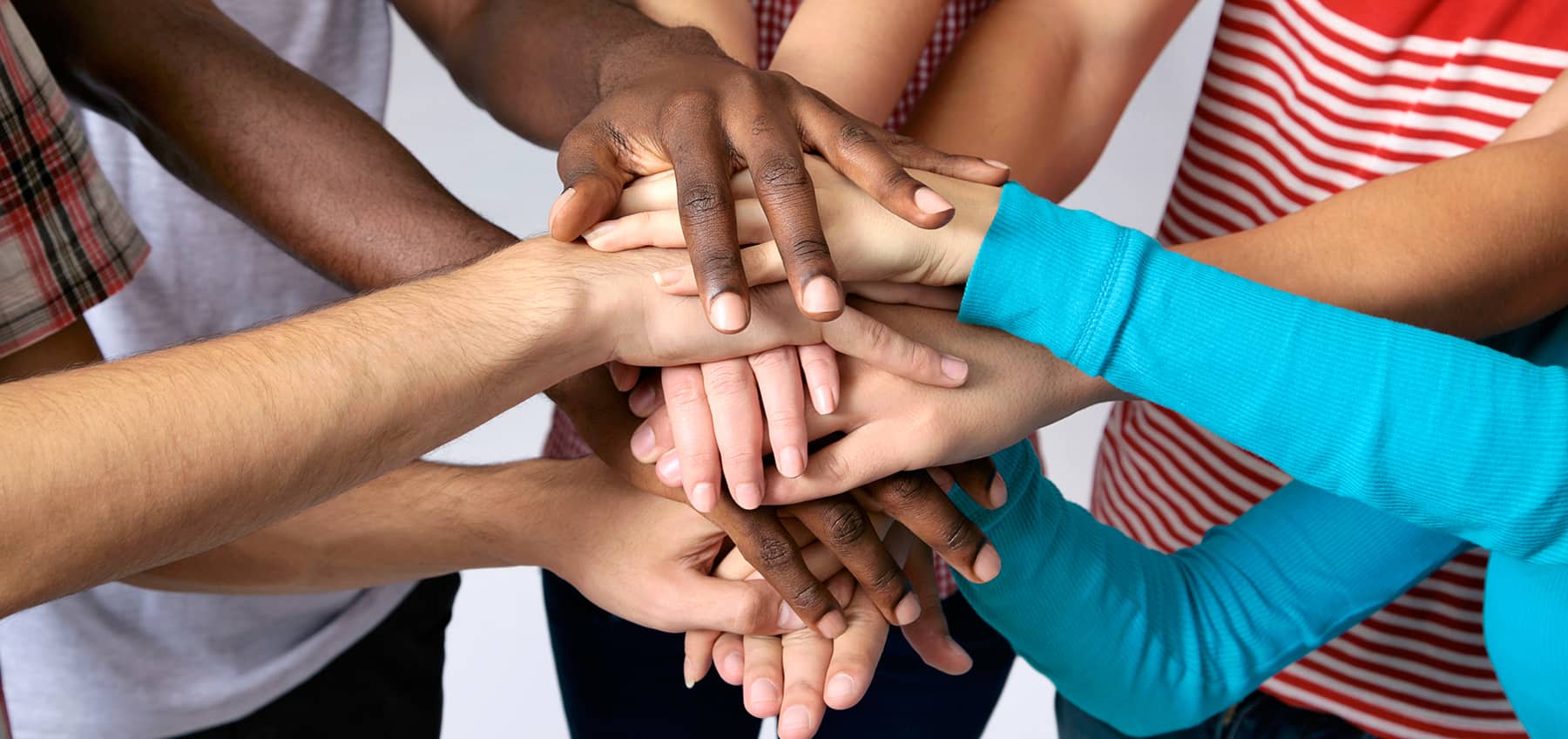 A variety of people from diverse backgrounds stacking hands