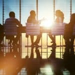 Adults sitting at a conference room table with the sun shining through leaving individuals in silhouette. Who is an employee and who is an independent contractor?