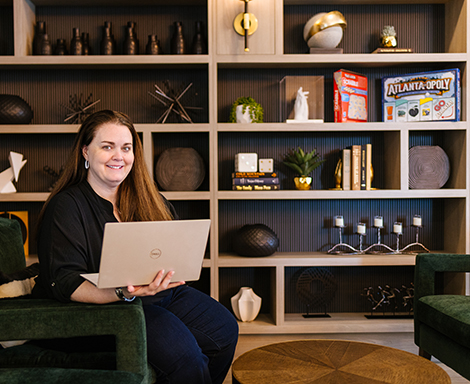 Law Firm growth expert Kimberly DeCarrera sits with a laptop in front of a bookshelf
